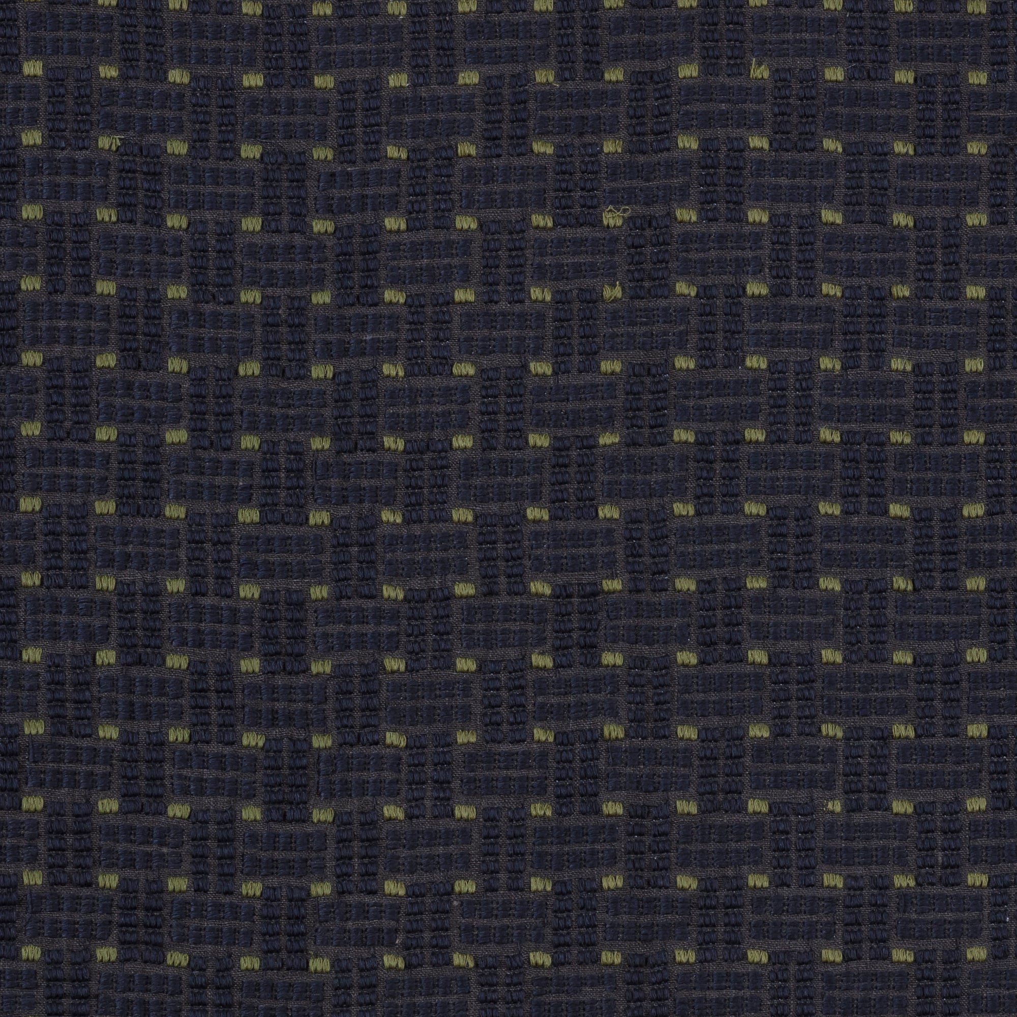 Detail of an embroidered fabric in a dashed basketweave design in navy blue with green accents.