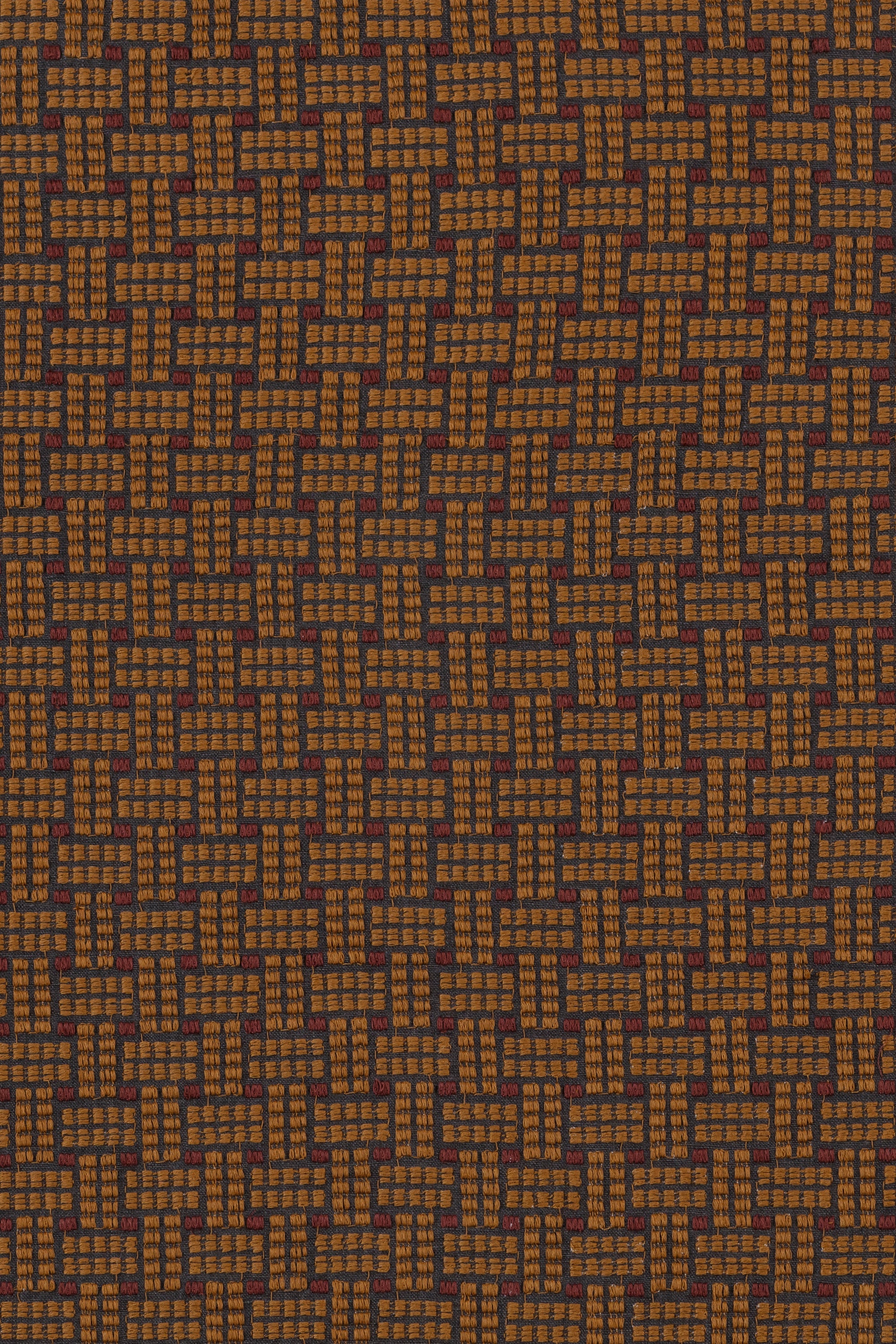 Embroidered fabric in a dashed basketweave design in caramel brown with red accents.