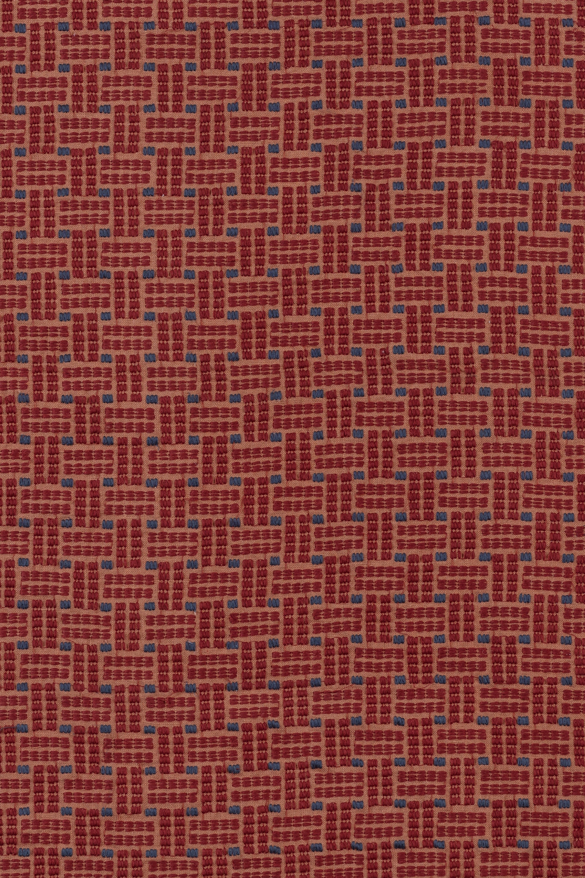 Embroidered fabric in a dashed basketweave design in red with blue accents.