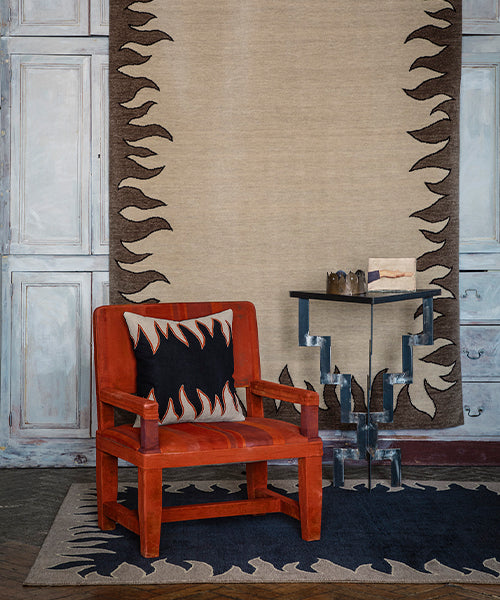 Red leather chair set against a Handknotted rug with a flame border design in brown on a cream field.