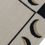 Detail of a flatweave rug with a crescent moon border in cream, taupe and black.