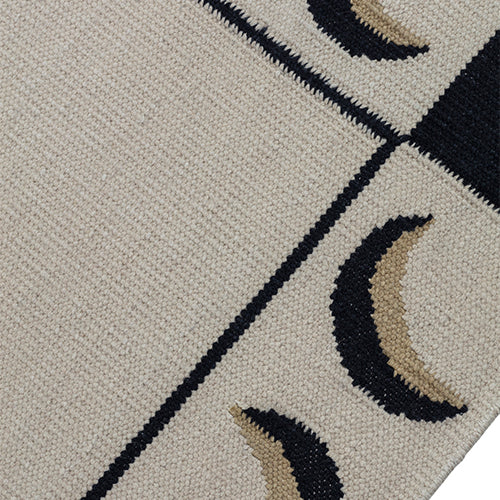 Detail of a flatweave rug with a crescent moon border in cream, taupe and black.