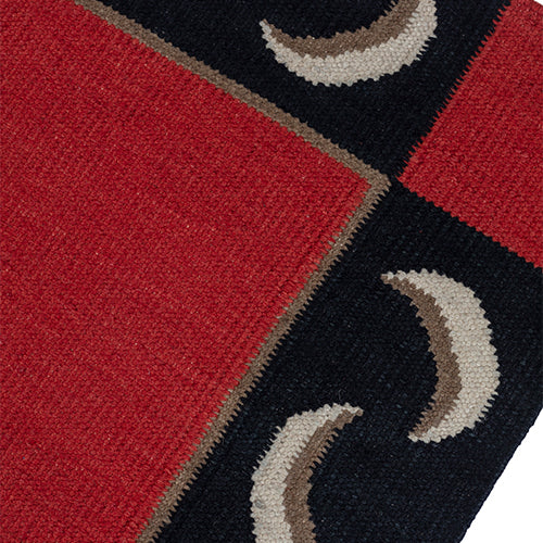 Detail of a flatweave runner with a crescent moon border in cream, taupe and black of a red field.