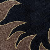 Detail of a handknotted rug with a flame border design in brown on a black field. 