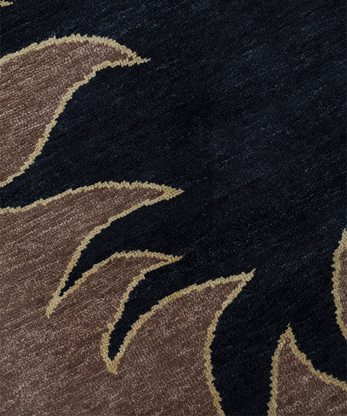 Detail of a handknotted rug with a flame border design in brown on a black field. 