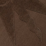 Detail of a handknotted rug with a raised sun motif in tonal brown.