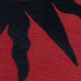 Detail of a handknotted rug with a raised sun motif in black on a red field.