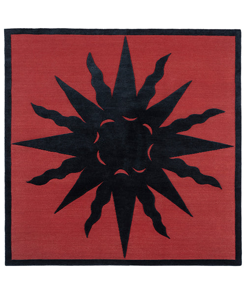 Handknotted rug with a raised sun motif in black on a red field with thin black border.