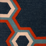 Detail of a flatwoven rug in a bold geometric floral-like design in blue, navy, red and cream. 