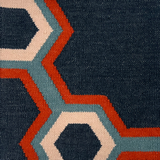 Detail of a flatwoven rug in a bold geometric floral-like design in blue, navy, red and cream. 
