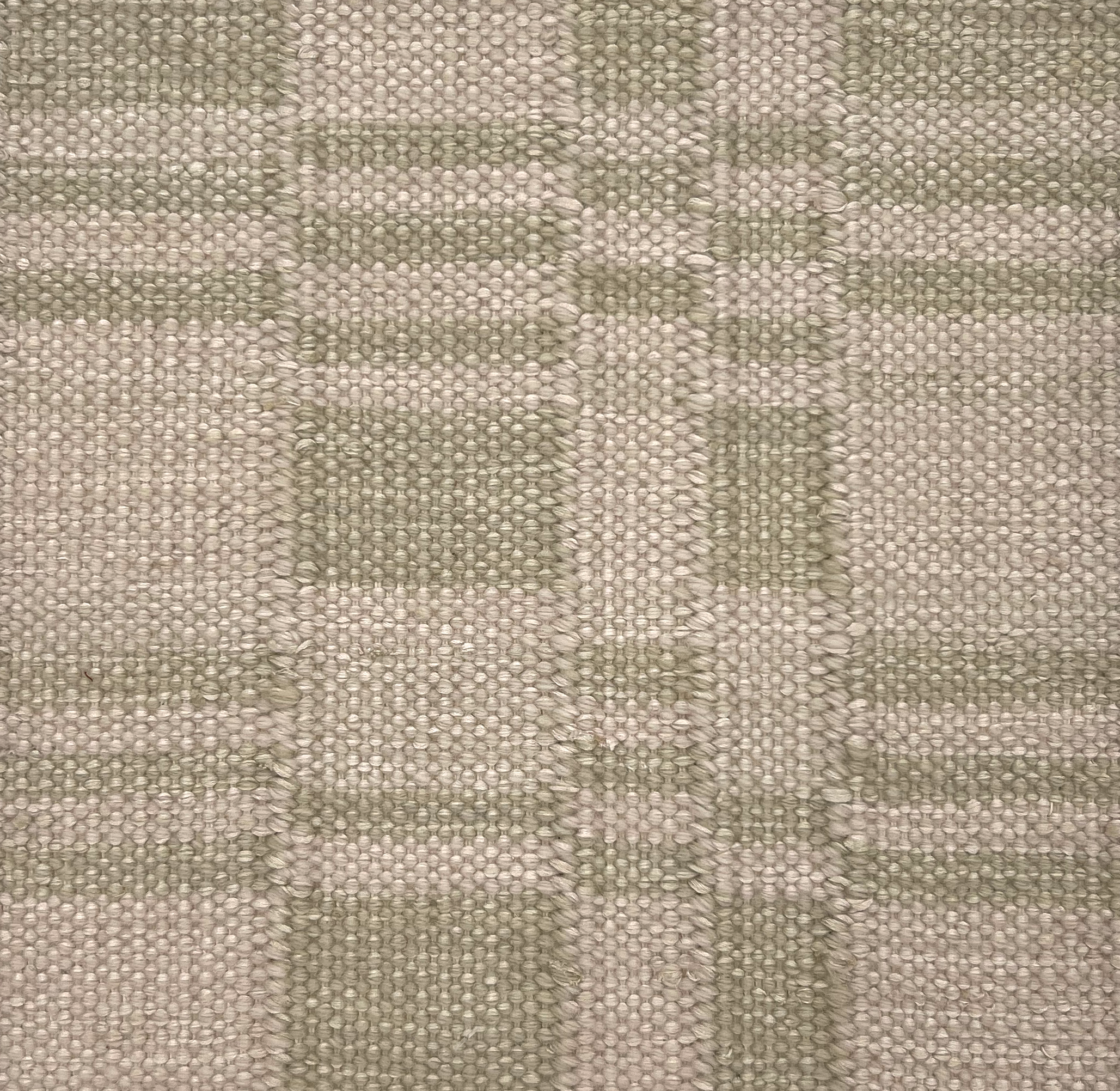 Flatwoven rug detail in a broken checkerboard design in ecru and sage green.