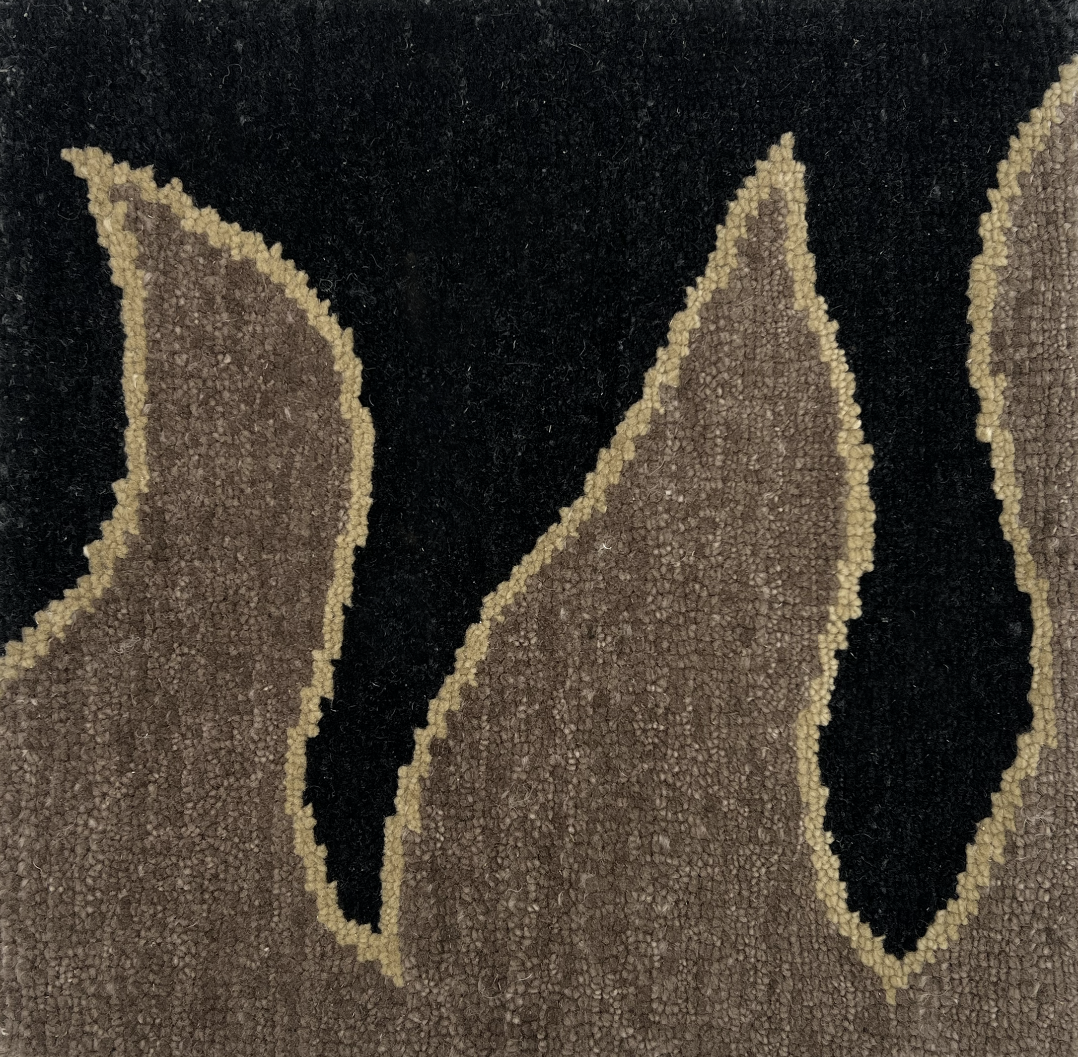 Detail of a handknotted rug with a flame border design in brown on a black field. 