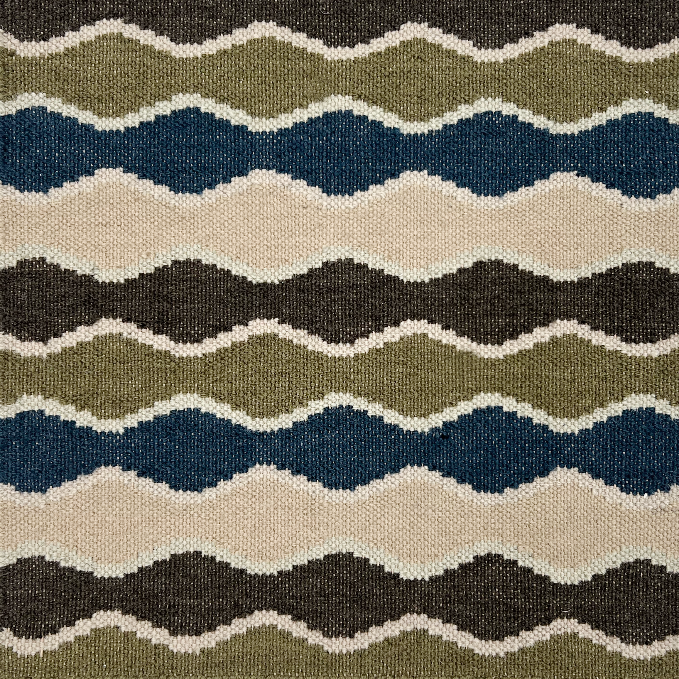 Deatil of a flatwoven rug in a wavy stripe pattern in green, blue, brown, cream and white. .