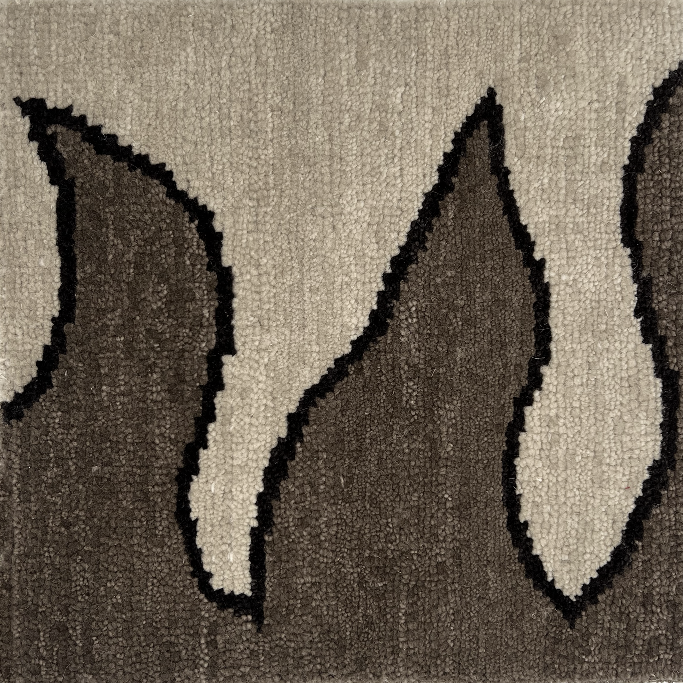 Detail of a handknotted rug with a flame border design in brown on a cream field.