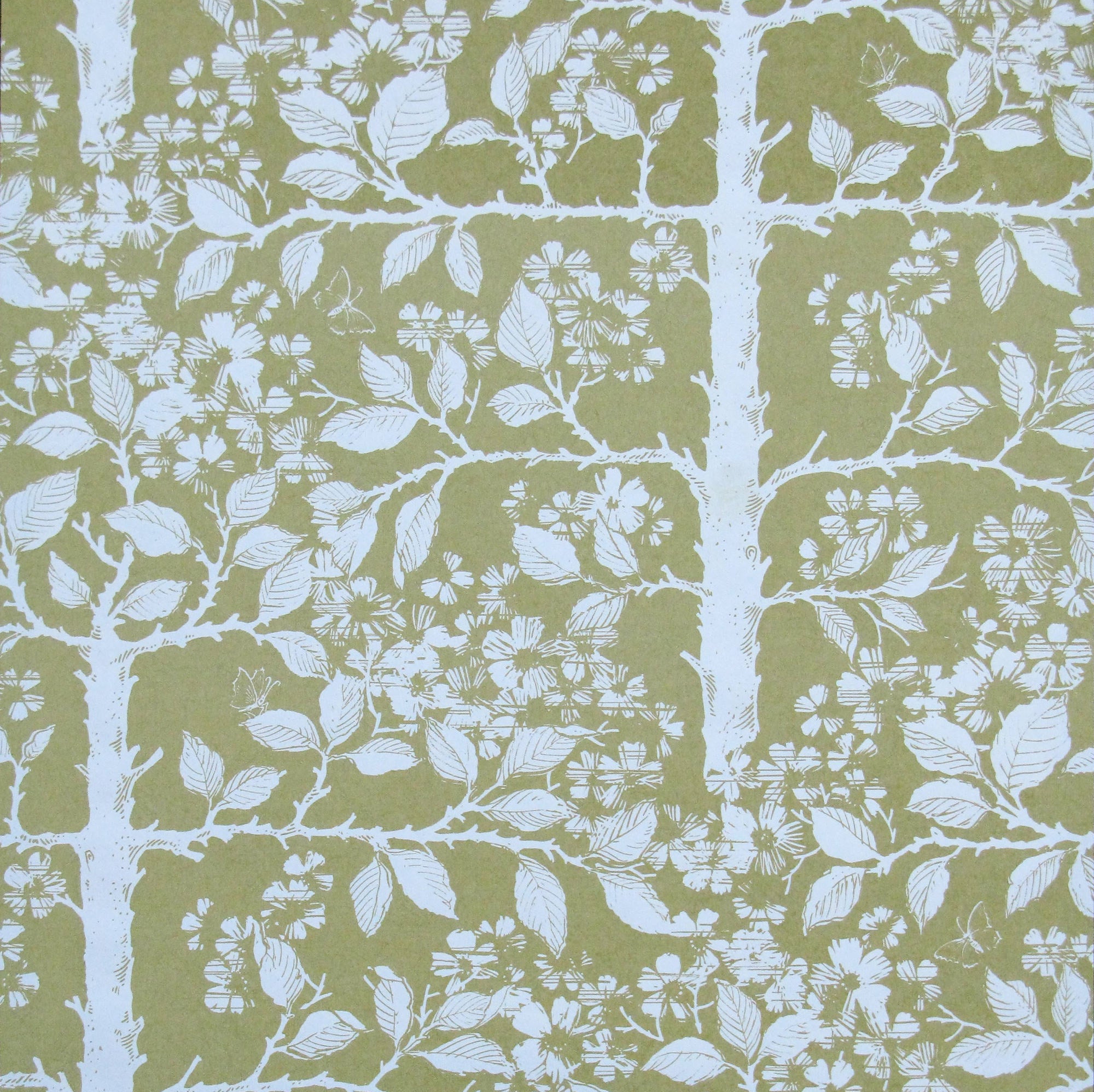 Detail of wallpaper in a large-scale tree and leaf print in white on a light green field.
