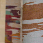 Detail of printed fabric in an engineered stripe design with watercolor effects in shades of turquoise, beige and brown.