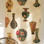 Rattan chair in front a of a printed fabric panel with ornate decorative urns.