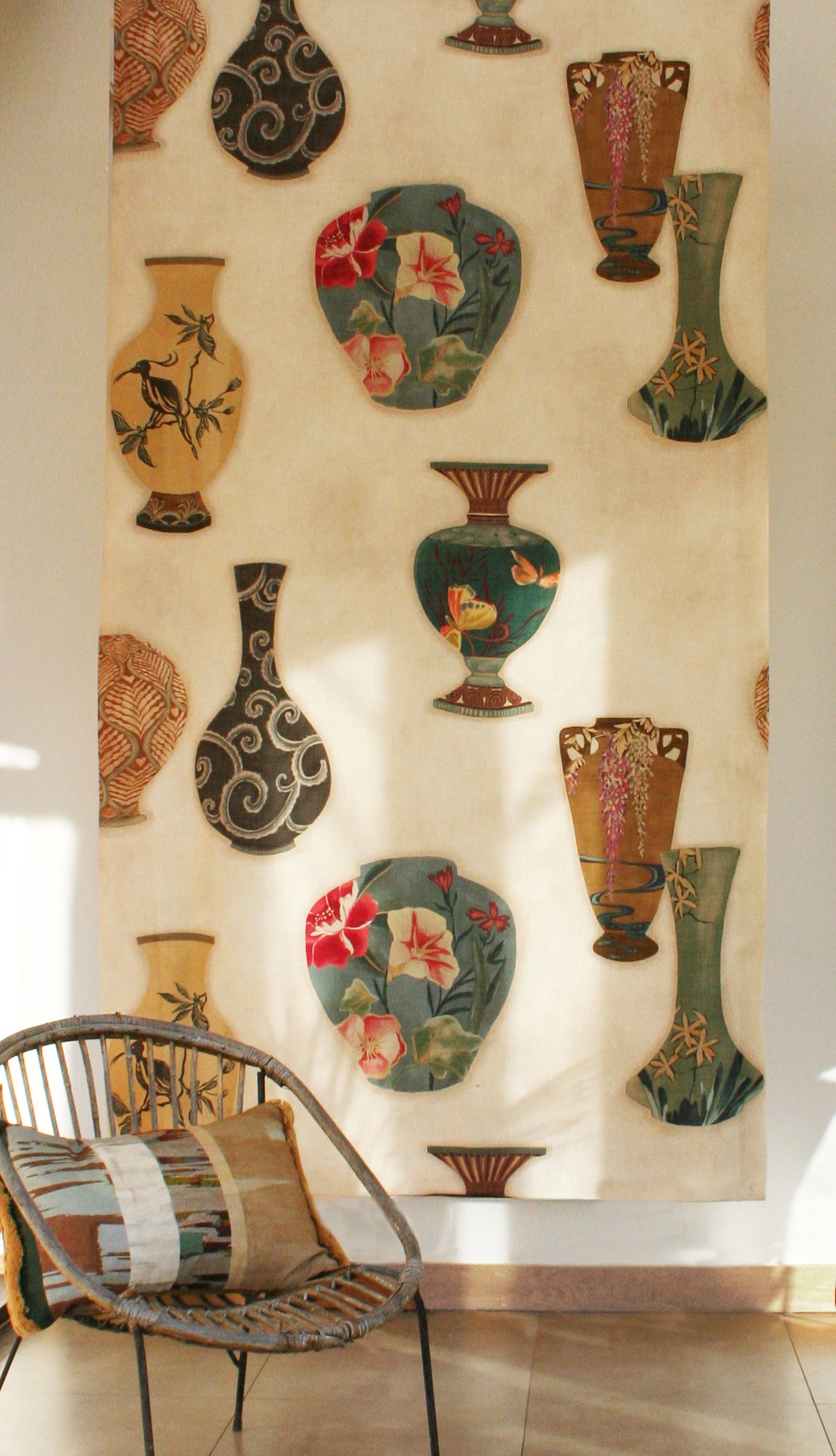 Rattan chair in front a of a printed fabric panel with ornate decorative urns.