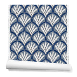 A hanging roll of wallpaper with a repeating Moroccan-inspired scallop pattern in navy and white on a blue background.