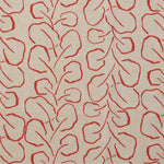 Woven fabric swatch with a large-scale repeating leaf print in red on a tan background.