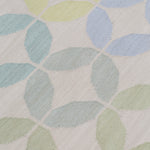 Detail of Alhambra Rug in Mint featuring a pattern of linked circles that create a star like lattice in a range of pastel turquoise, mint, yellow and lime green on a soft beige field. 