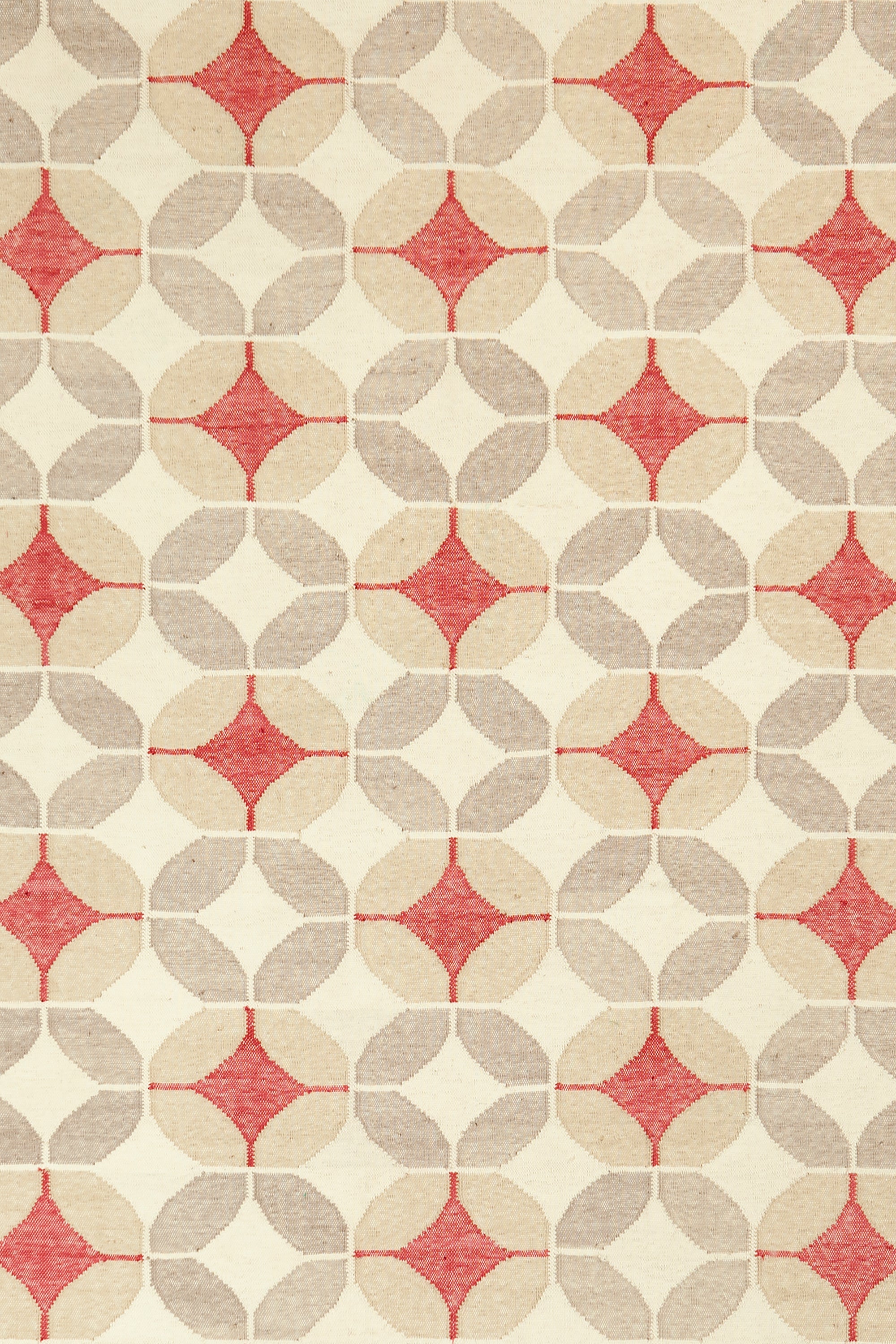 Detail of Alhambra Rug in Tomato featuring pattern of linked circles that create a star like lattice in a range of tan, beige, ecru and bright red on a soft white field. 
