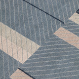 Detail of the Amelia Rug in Lapiz featuring a minimalist broken stripe pattern, overlayed with thin light blue diagonal lines. The broken stripes are a mix of navy blue, pale blue. white and turquoise with black accents, all on denim blue field.