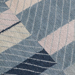 Detail of the Amelia Rug in Lapiz featuring a minimalist broken stripe pattern, overlayed with thin light blue diagonal lines. The broken stripes are a mix of navy blue, pale blue. white and turquoise with black accents, all on denim blue field.