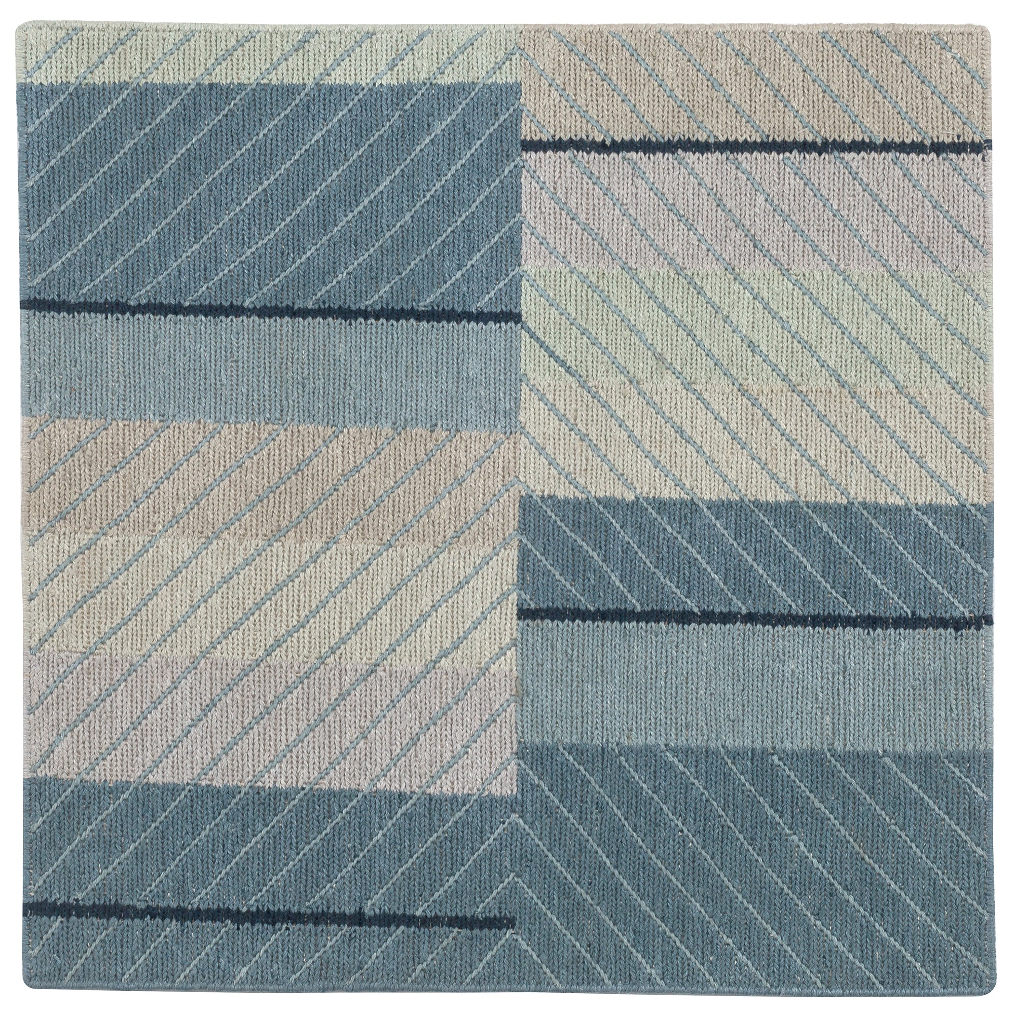 Detail of the Amelia Rug in Lapiz featuring a minimalist broken stripe pattern, overlayed with thin light blue diagonal lines. The broken stripes are a mix of navy blue, pale blue. white and turquoise with black accents, all on denim blue field.