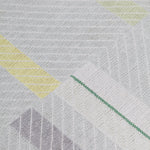 Detail of the Amelia Rug in Peridot featuring a minimalist broken stripe pattern, overlayed with thin white diagonal lines. The broken stripes are a mix of white, grey, and shades of yellow with kelly green accents, all on a light grey field. 