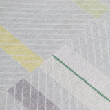 Detail of the Amelia Rug in Peridot featuring a minimalist broken stripe pattern, overlayed with thin white diagonal lines. The broken stripes are a mix of white, grey, and shades of yellow with kelly green accents, all on a light grey field. 