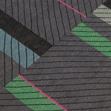 Detail of the Amelia Rug in Spinel featuring a minimalist broken stripe pattern, overlayed with thin black diagonal lines. The broken stripes are a mix of white, grey, kelly green, denim blue, black with hot pink accents, all on a charcoal grey field. 