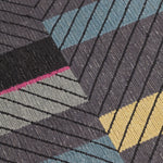 Detail of the Amelia Rug in Spinel featuring a minimalist broken stripe pattern, overlayed with thin black diagonal lines. The broken stripes are a mix of white, grey, kelly green, denim blue, black with hot pink accents, all on a charcoal grey field. 
