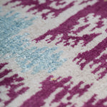 Detail of the Anna Ikat rug in Cranberry features an ikat inspired pattern of diamonds in blue and white with pale lime green accents on a magenta field