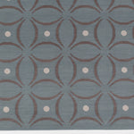 Detail of the Boe rug in Argento, featuring a pattern of curved segments in grey with white circles on a blue field. 