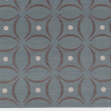 Detail of the Boe rug in Argento, featuring a pattern of curved segments in grey with white circles on a blue field. 