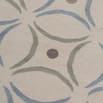 Detail of the Boe rug in Genoa, featuring a pattern of curved segments in light blue and sage green with taupe circles on an ivory field. 