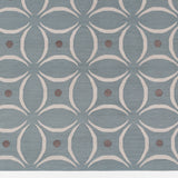 Detail of the Boe rug in Argento, featuring a pattern of white curved segments with taupe circles on a blue field. 