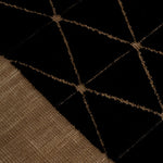 Detail of the Bucky Rug in jet-tan, features a wide taupe border with a black lattice field with a metallic sheen. 