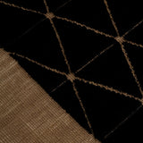 Detail of the Bucky Rug in jet-tan, features a wide taupe border with a black lattice field with a metallic sheen. 