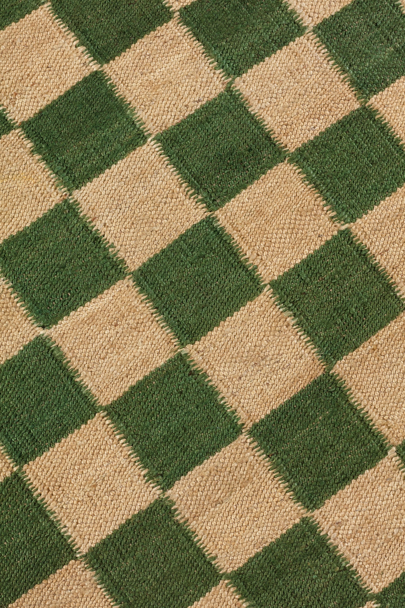 Detail of the Checkerboard Rug in Pawn, a green and tan checkered pattern. 