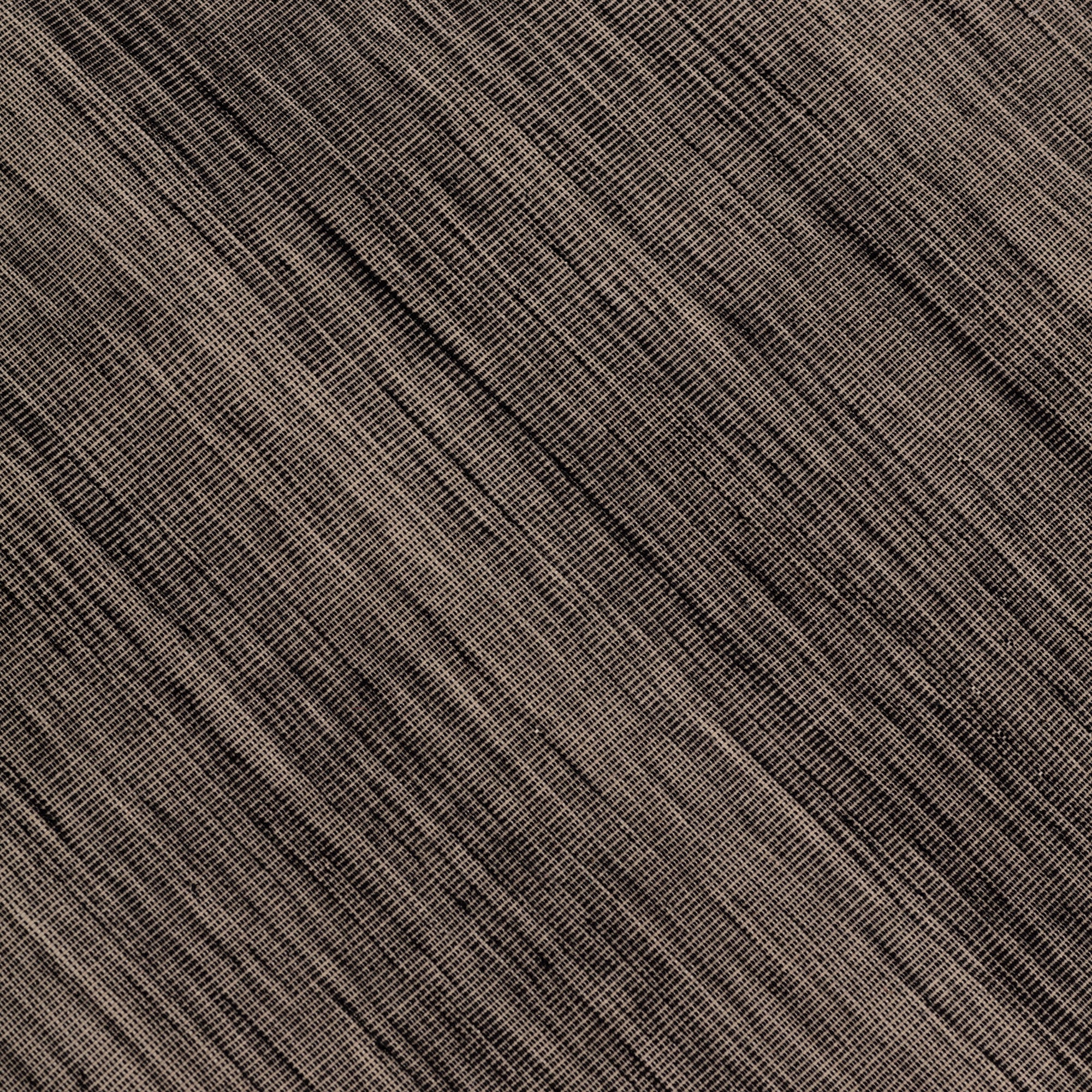 Detail of the Moire Rug in Rockpool, a subtle striated pattern tan and black. 