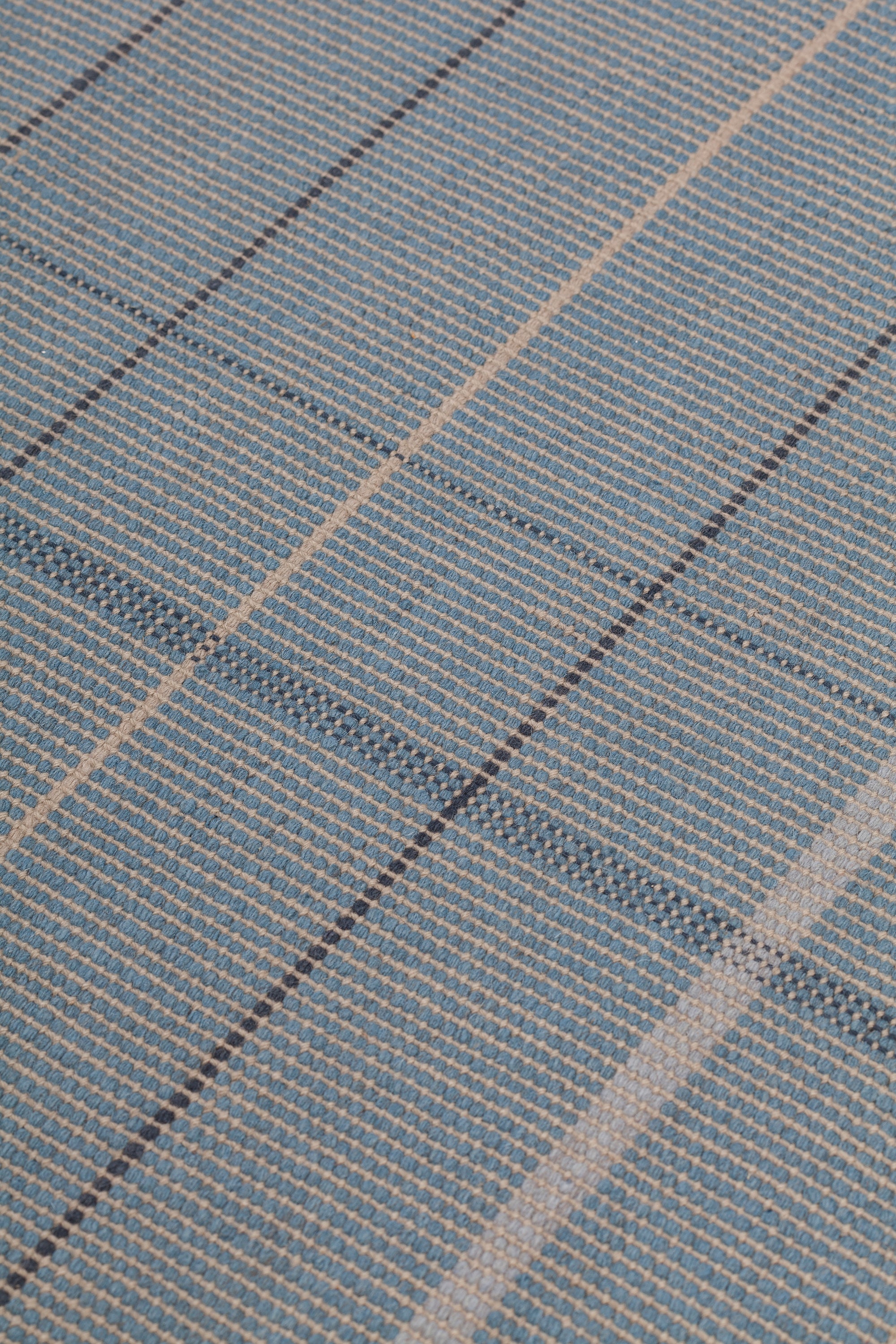 Detail of the Jasper Waffle Rug in Chalcedony, a large scale plaid pattern of denim blue, black, yellow and pale turqouise. 