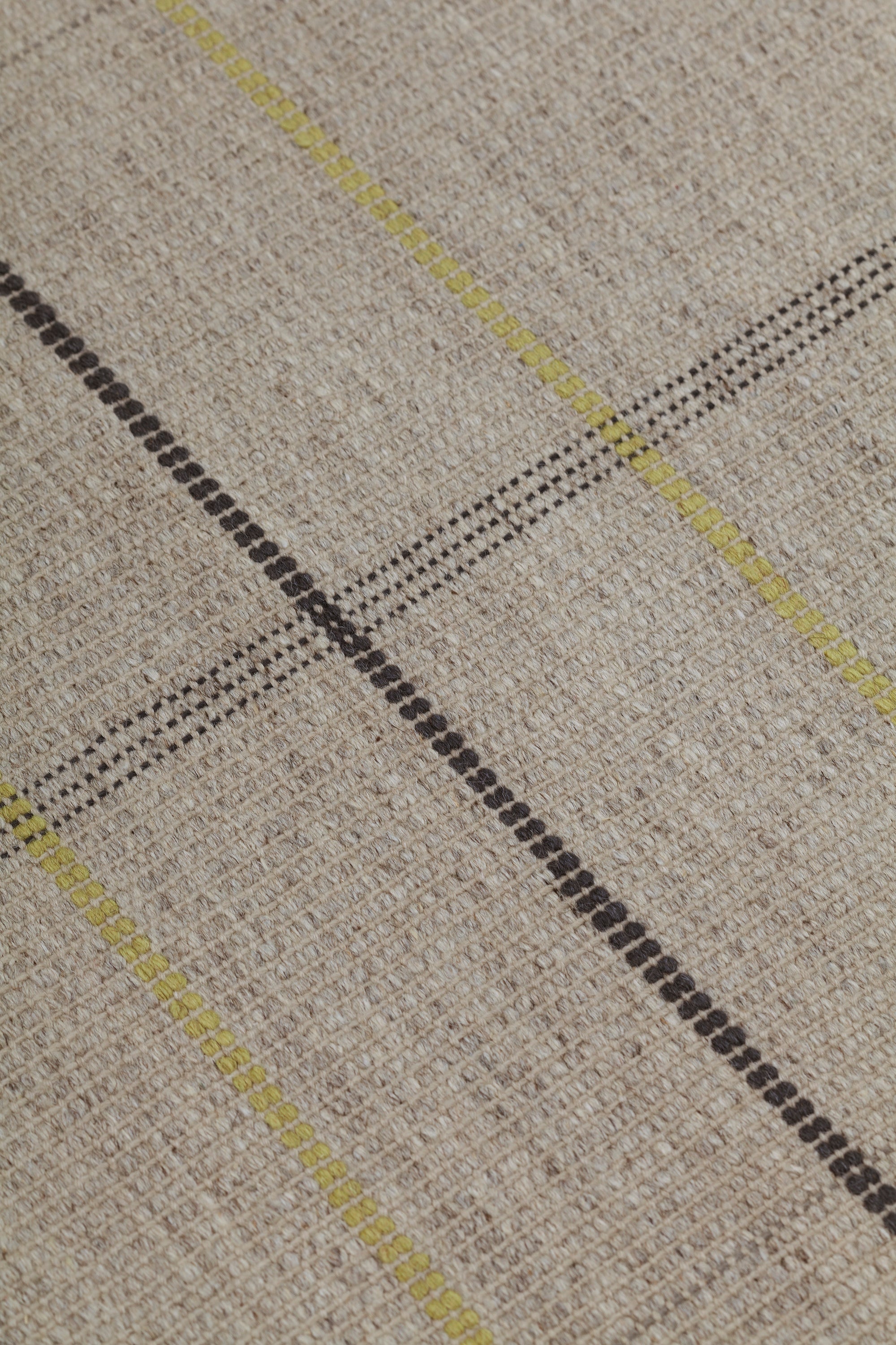 Detail of the Jasper Waffle Rug in Peridot, a large scale plaid pattern of ecru, yellow, grey and off white. 