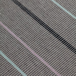 Detail of the Jasper Waffle Rug in Jet, widely spaced thin stripes of yellow, pink, black, acqua and white on a grey field. 