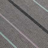 Detail of the Jasper Waffle Rug in Jet, widely spaced thin stripes of yellow, pink, black, acqua and white on a grey field. 