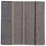 Detail of the Jasper Waffle Rug in Jet, widely spaced thin stripes of yellow, pink, black, acqua and white on a grey field. 