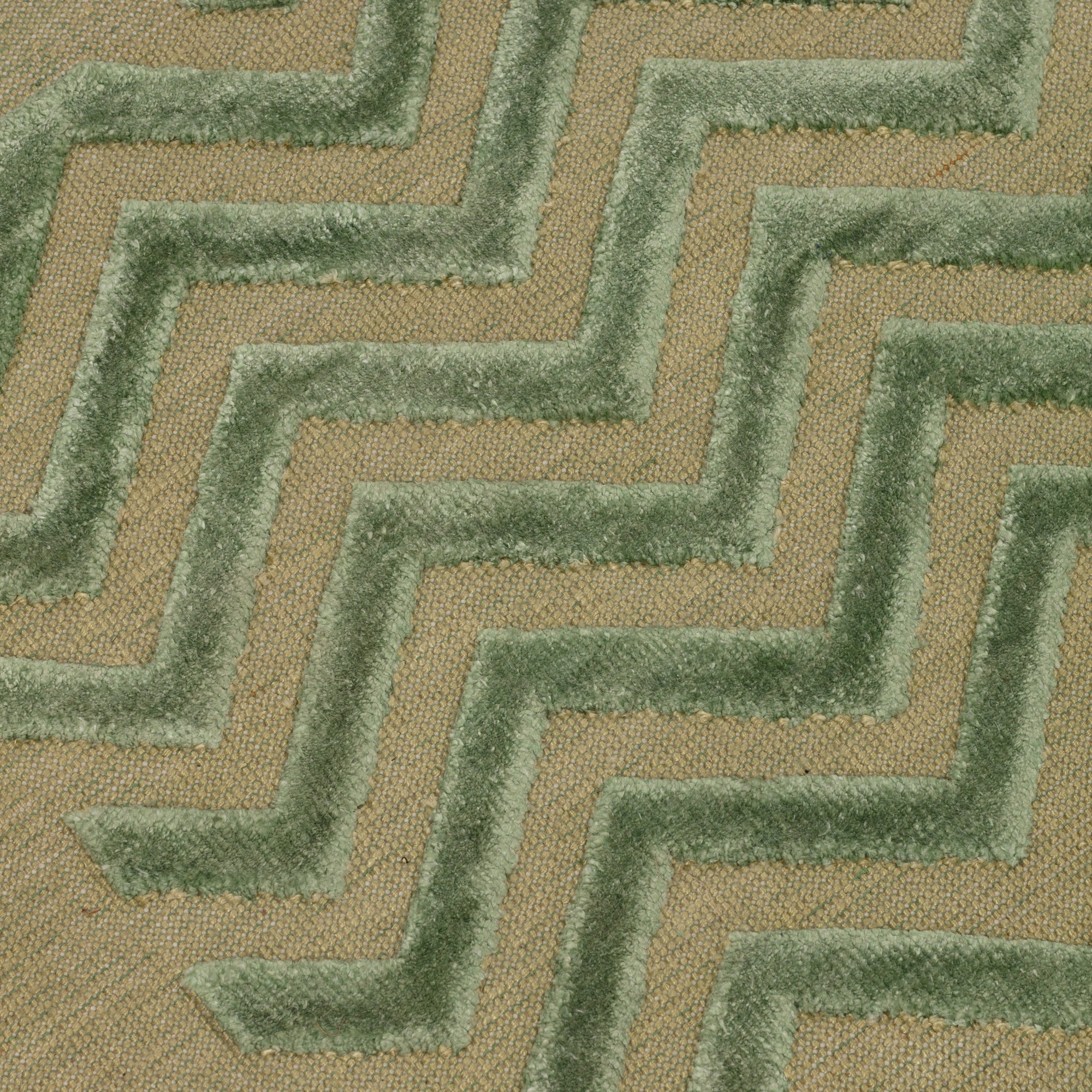 Detail of the Penta Chevron Rug in Pale Jade a light green chevron pattern on a lime green  field with a wide solid border. 