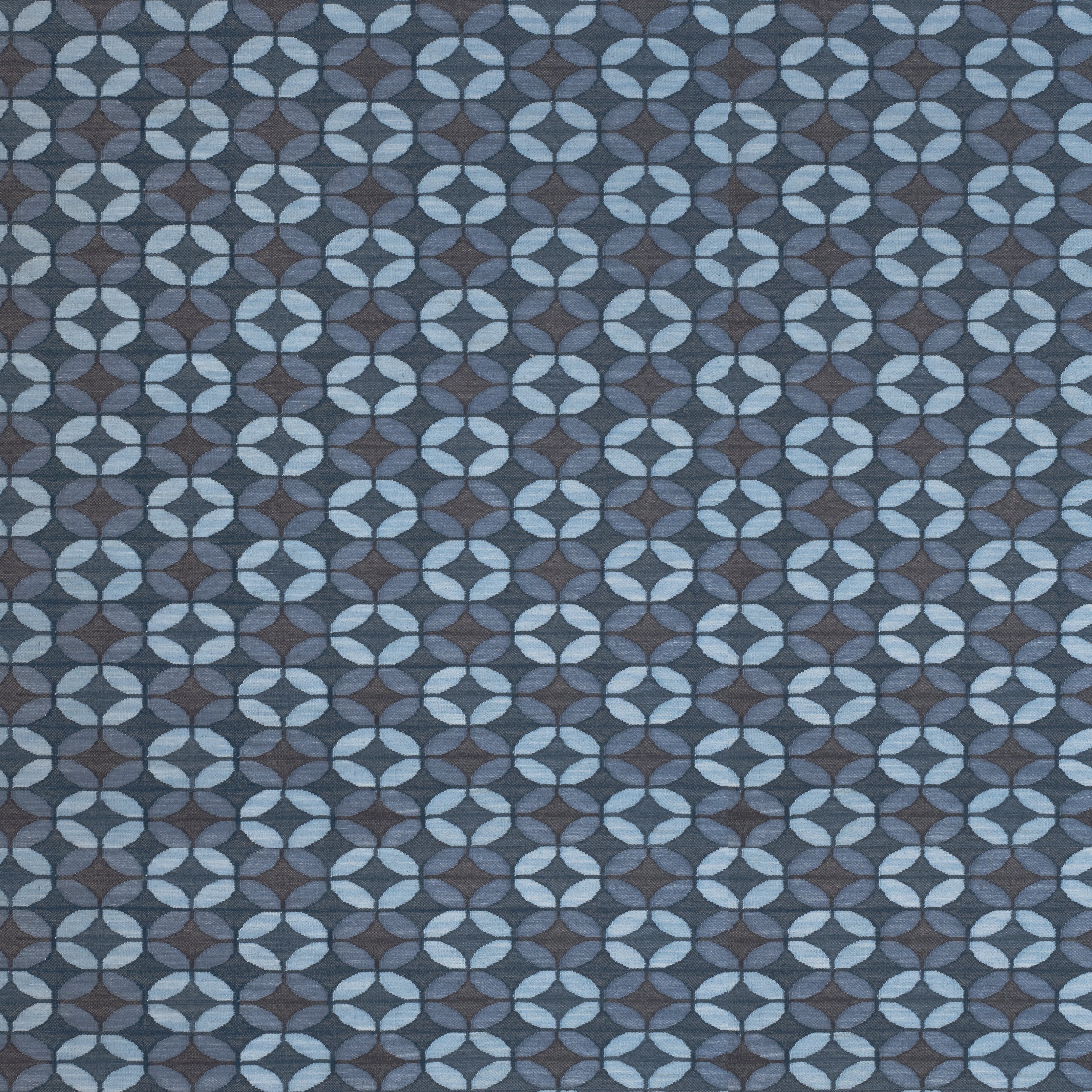 Petite Alhambra Rug featuring a pattern of linked circles that create a star like lattice in a range of blue shades, from pale blue to chambray, indigo, to dark navy