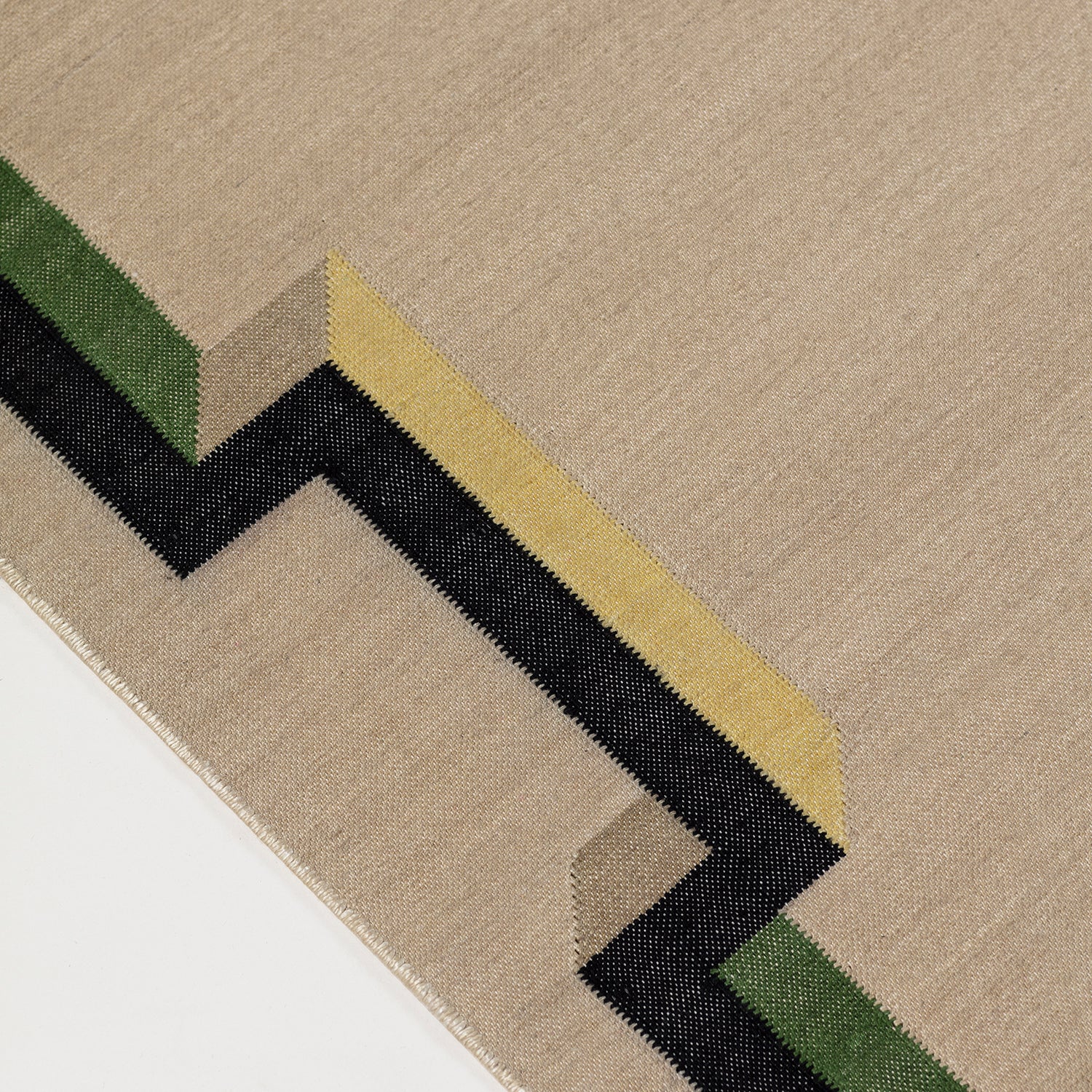 Detail of the Ponti Rug in Salvia, an ivory field with a geometric stair step border in black, with yellow, green and taupe. 